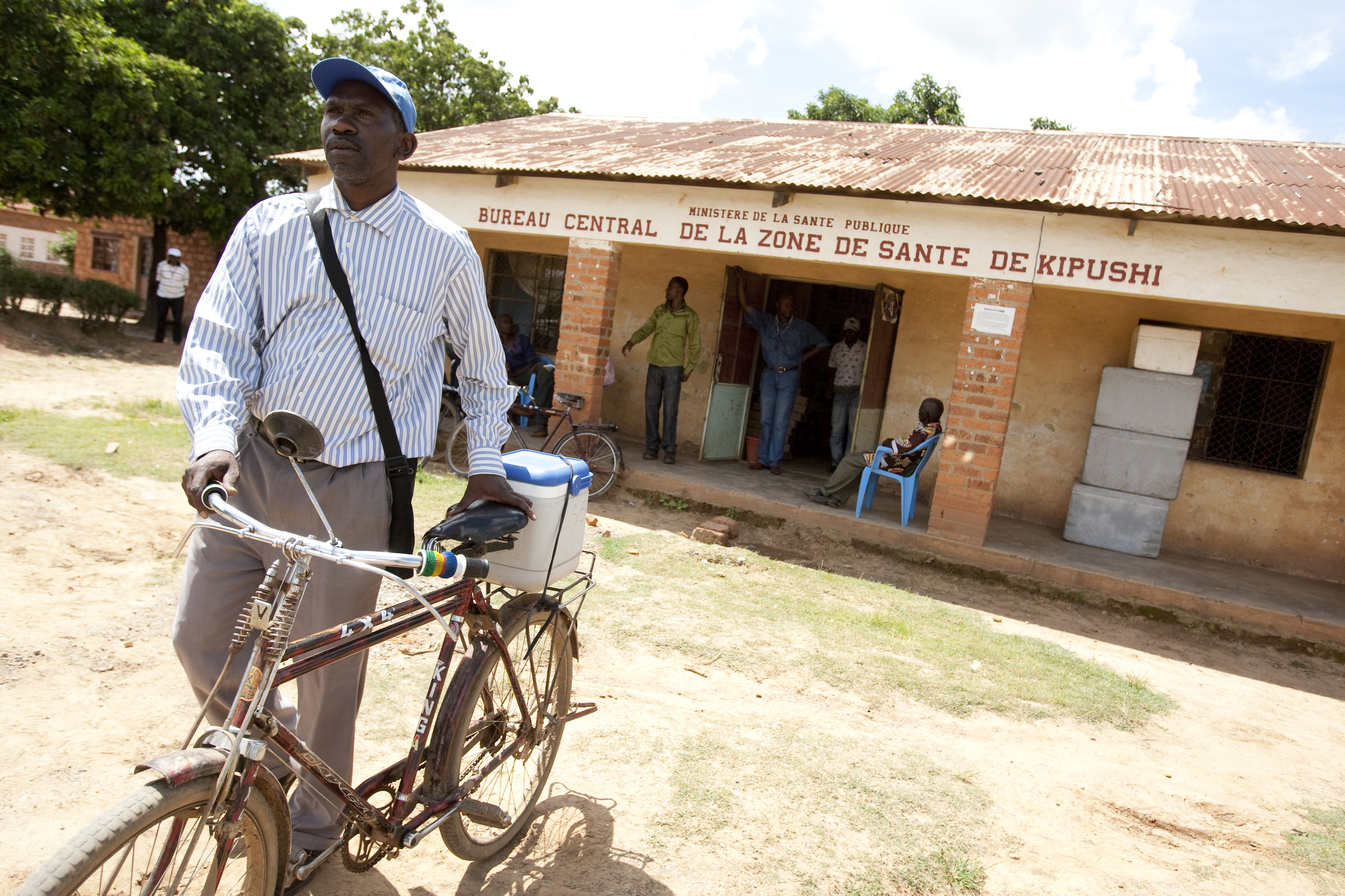 Assistant nurse Guy Bakatumaka pushes a bicycle carrying an icebox full of vaccines in DRC.