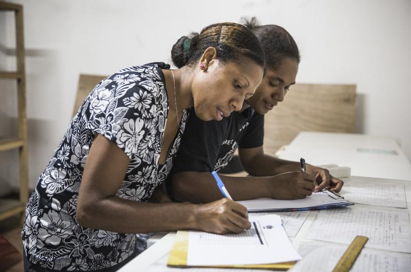 Supply chain workers writing at a desk